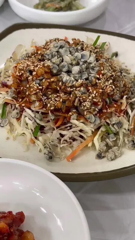 재첩회무침의 클로즈업, 깨가 듬뿍 뿌려져 있다.