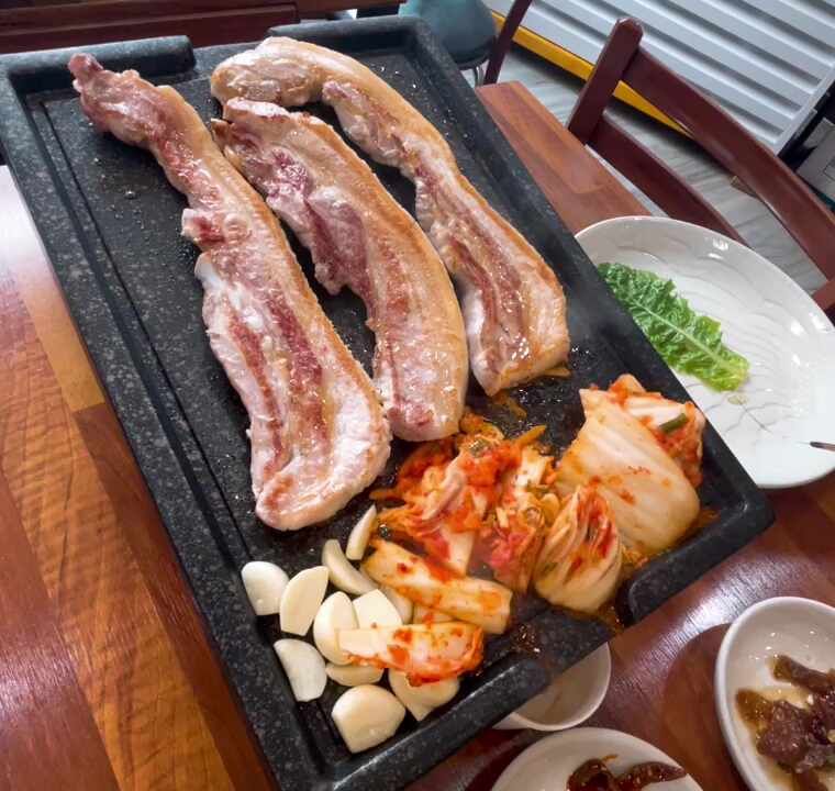 불판 위의 삼겹살과 김치, 마늘