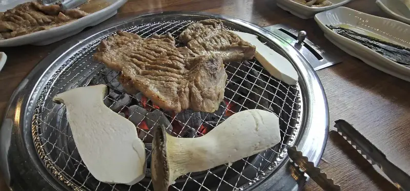 숯불 위에서 구워지는 돼지갈비와 버섯