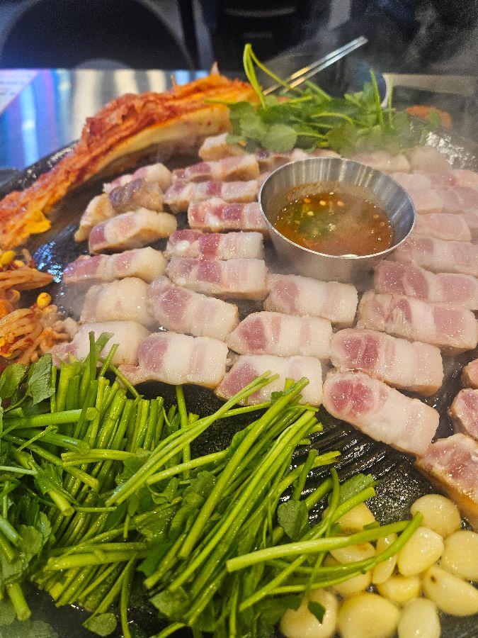 솥뚜껑에 푸짐하게 담겨 나온 삼겹살 한 상 차림