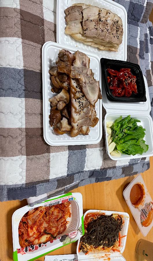 플라스틱 용기에 담긴 족발과 보쌈, 김치, 막국수, 쌈 채소, 소스