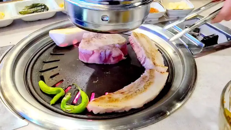 불판 위에서 익어가는 삼겹살과 김치