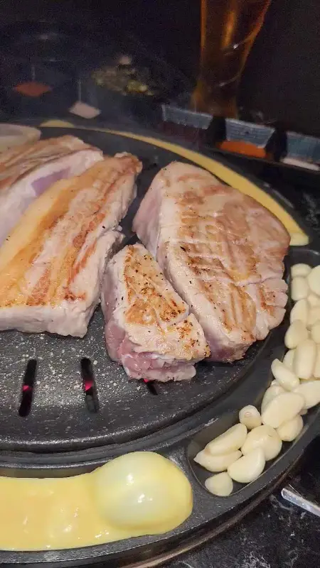 철판 가장자리에 구워지고 있는 마늘과 삼겹살