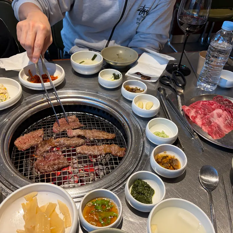 테이블 위에서 구워지는 고기와 와인잔