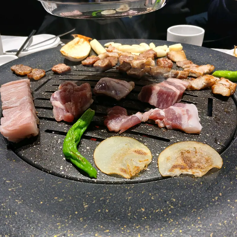 숯불 위에서 맛있게 익어가는 두툼한 고기의 모습