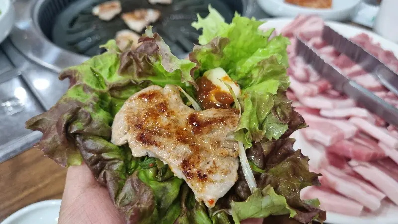 쌈 채소에 싸 먹는 삼겹살의 클로즈업 샷