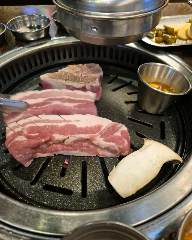 불판 위에서 맛있게 익어가는 삼겹살과 새송이버섯