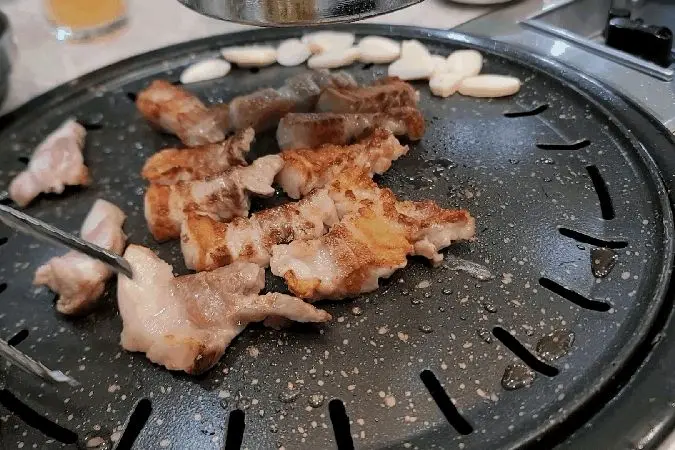 초벌된 삼겹살이 석쇠 위에서 맛있게 구워지는 모습