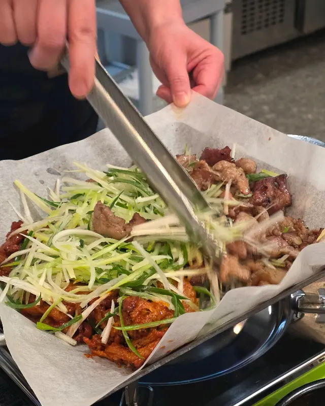 고추장 불고기와 파채를 집게로 집어 올리는 모습