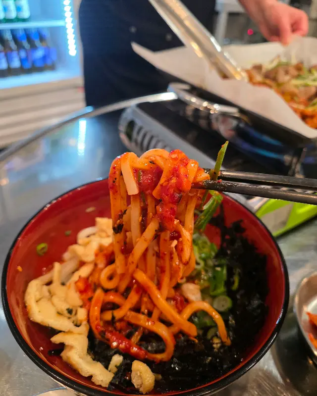 젓가락으로 비빔 우동을 들어 올리는 모습