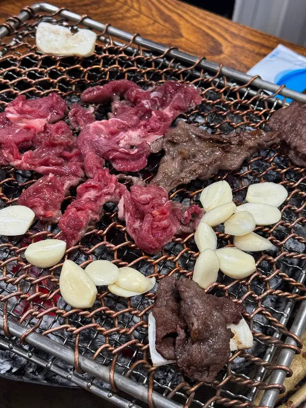 석쇠 위에서 불고기와 마늘이 함께 구워지고 있는 모습