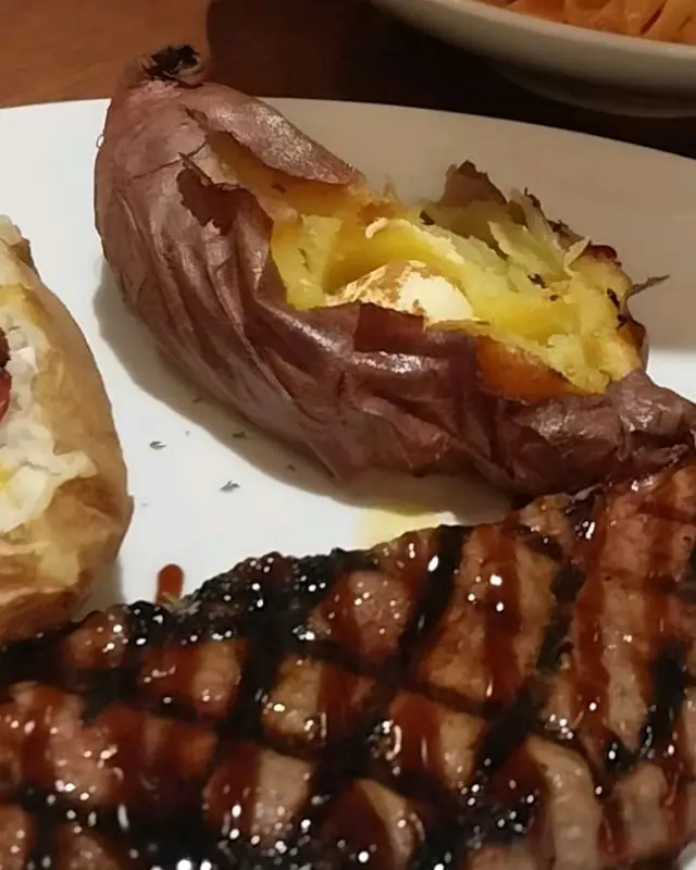 스테이크와 함께 구운 고구마가 놓여 있는 모습