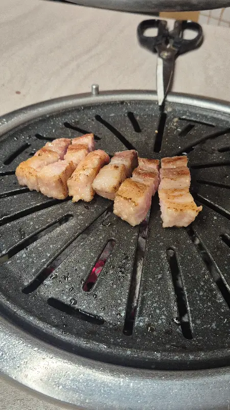 잘 익은 삼겹살이 먹기 좋게 잘려져 불판 위에 놓여있는 모습