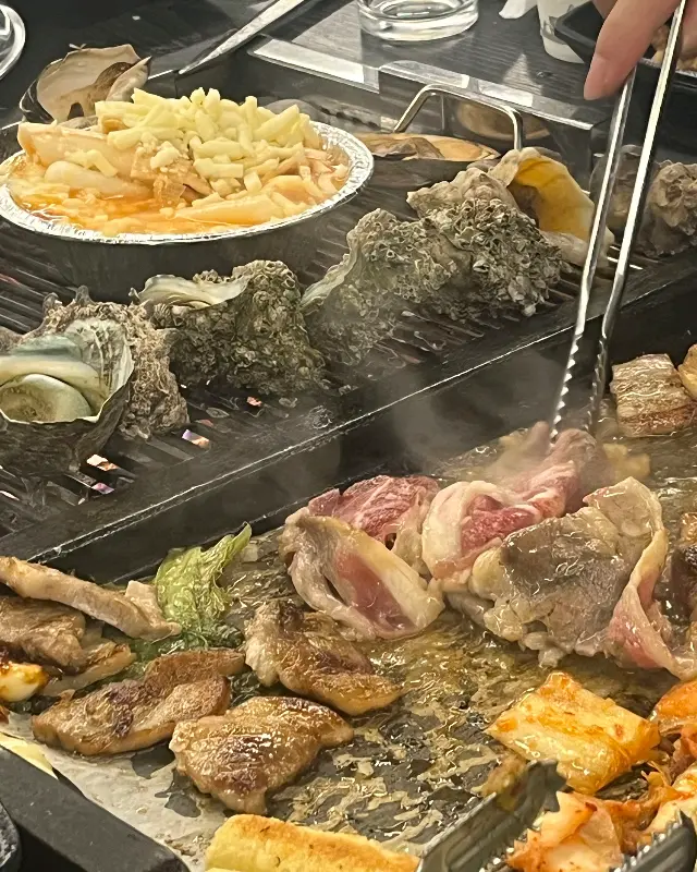불판 위에서 익어가는 다양한 해산물과 고기
