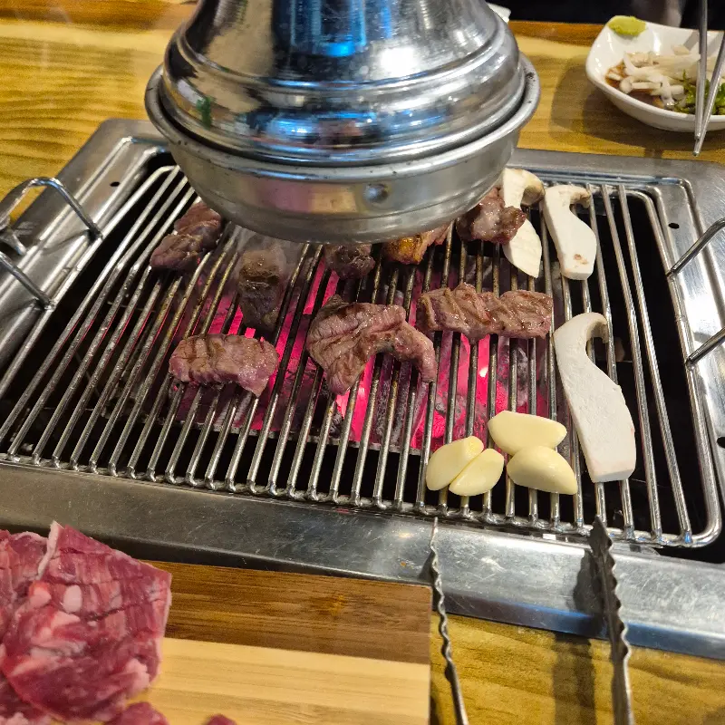 숯불 위에서 맛있게 익어가는 갈매기살과 버섯