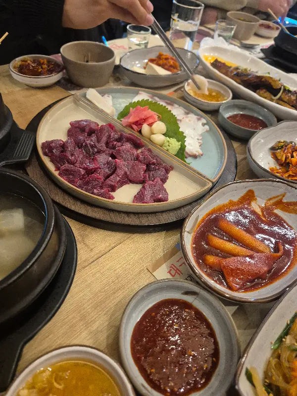 젓가락으로 뭉티기를 집어 양념장에 찍어 먹는 모습