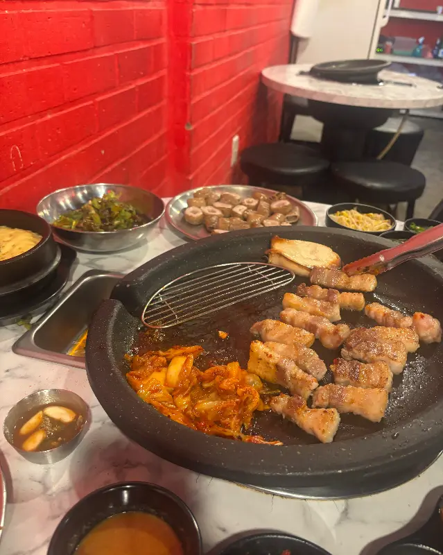 불판 위에서 맛있게 구워지고 있는 삼겹살과 김치