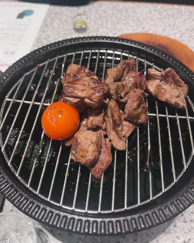 불판 위에서 구워진 돼지고기와 방울토마토의 먹음직스러운 모습