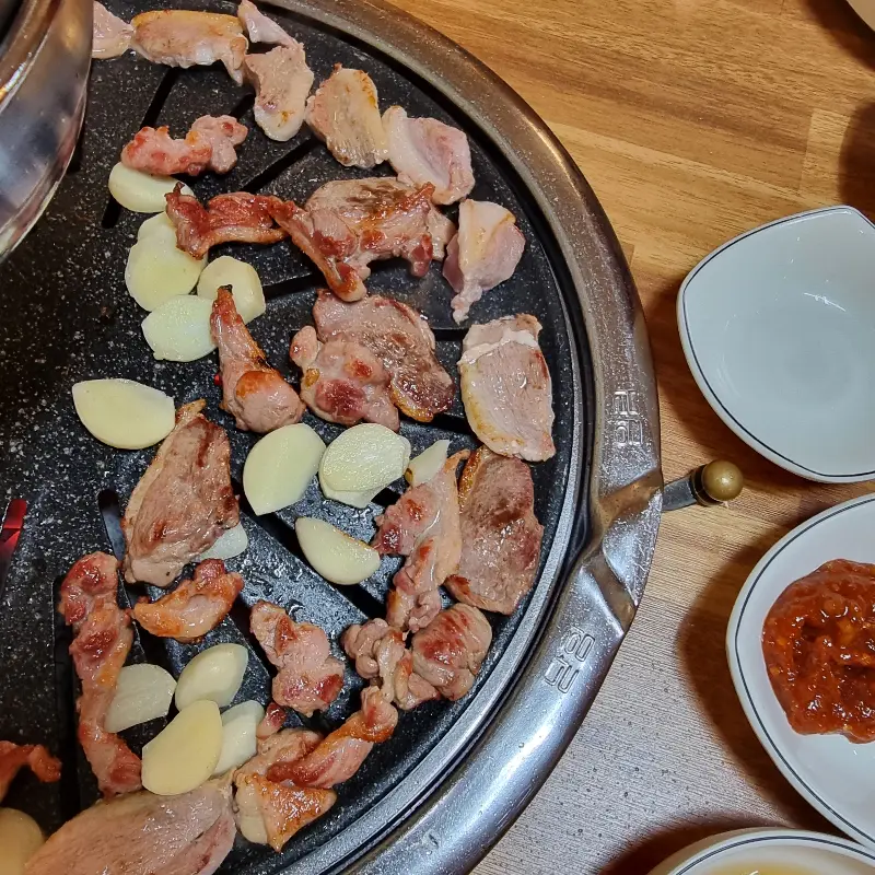 숯불 위에서 맛있게 익어가는 오리고기와 마늘