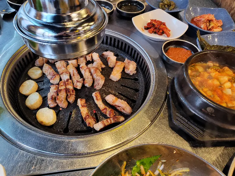 불판 위에서 노릇하게 익어가는 삼겹살과 떡