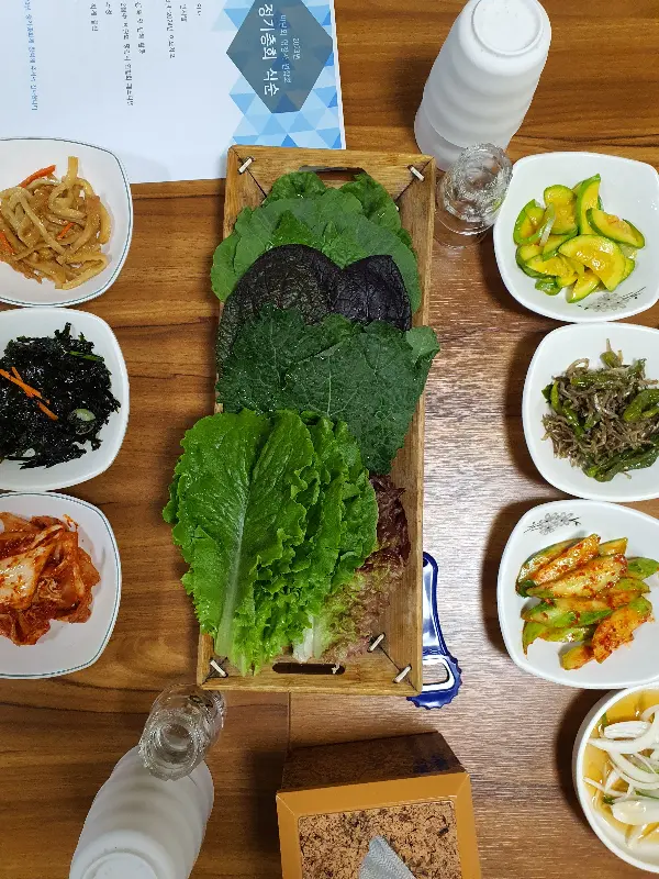 다채로운 쌈 채소와 정갈한 반찬들이 차려진 테이블