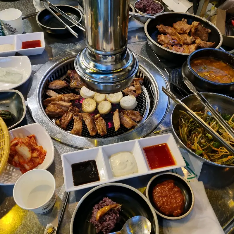 불판 위에서 익어가는 닭갈비와 버섯, 그리고 다양한 곁들임