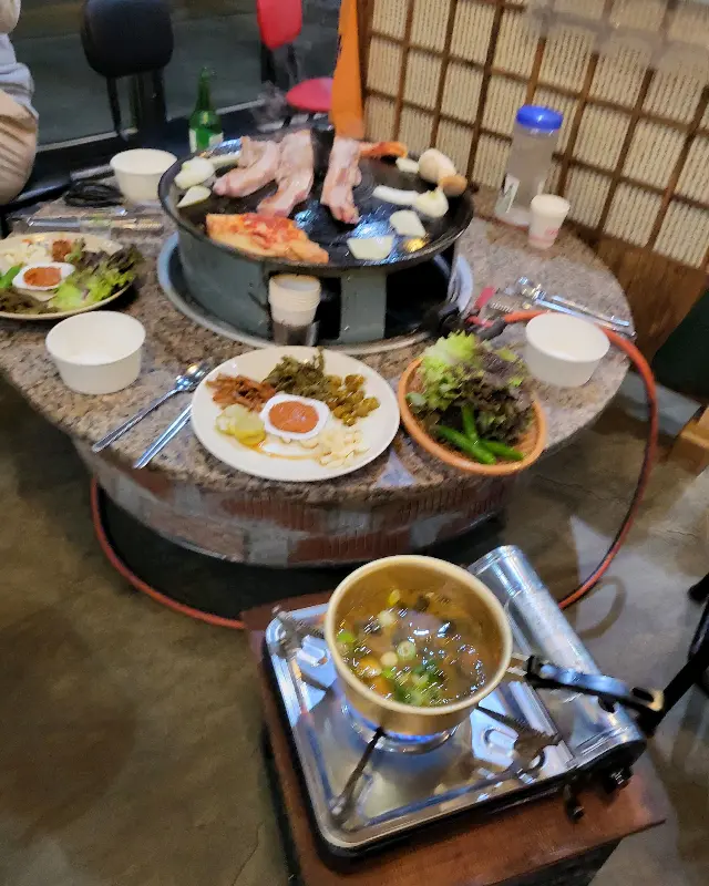 솥뚜껑에 오겹살과 김치를 구워 먹는 모습