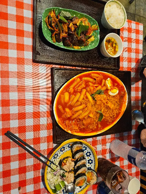 테이블 위에 놓인 라볶이, 김밥, 제육덮밥