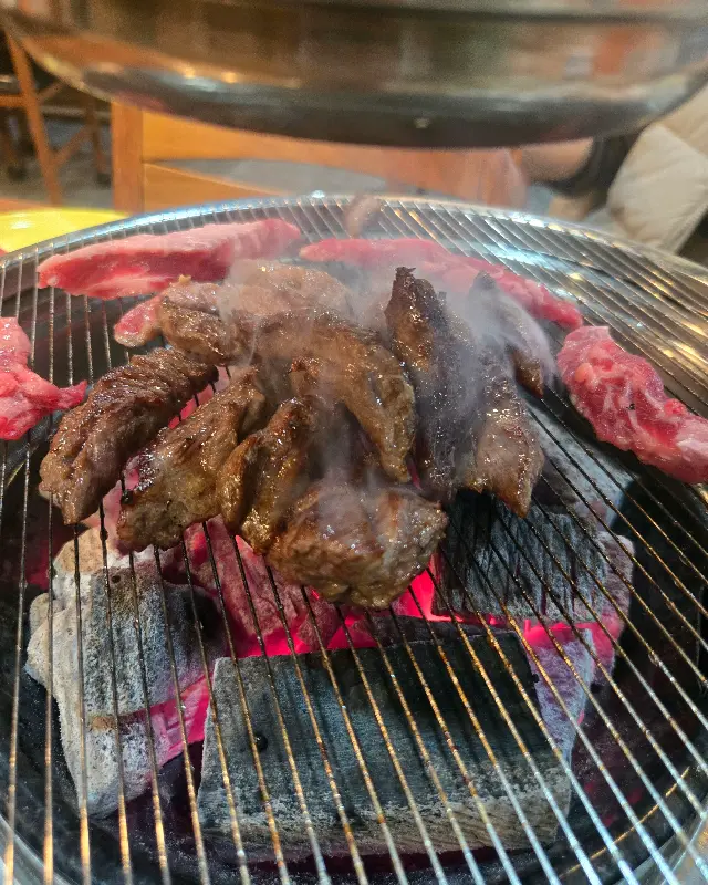 숯불 위에서 연기를 내뿜으며 익어가는 소고기