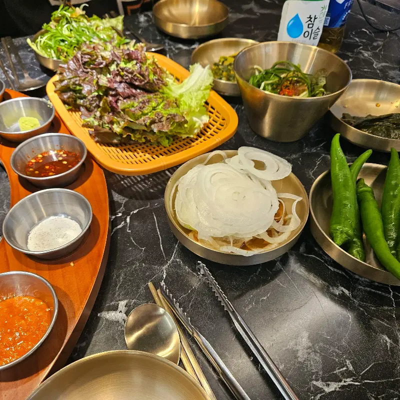 다채로운 밑반찬이 정갈하게 담겨 테이블 위에 놓여있는 모습