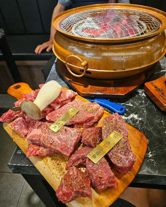 테이블에 놓인 화로 위 석쇠에 여러 종류의 소고기가 구워지기 전 담겨져 있는 모습