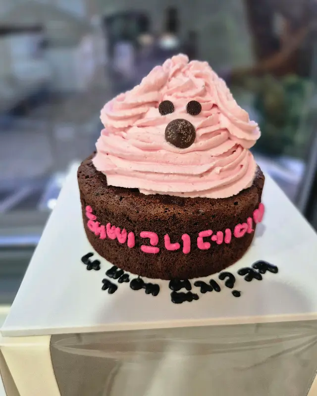 귀여운 표정의 핑크 크림 케이크