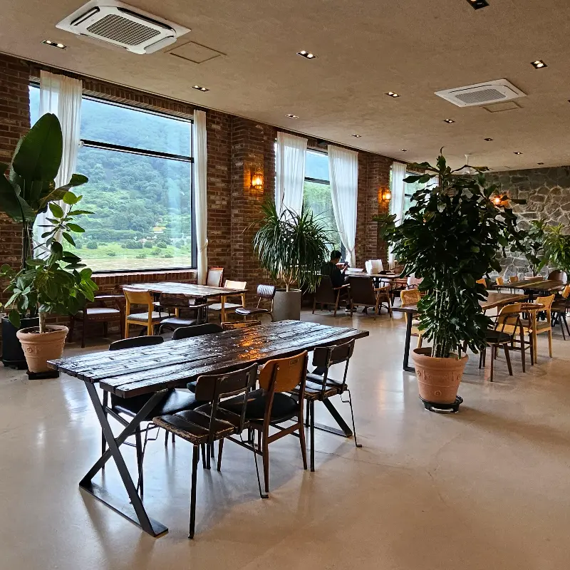 넓고 아늑한 카페 내부, 창밖으로 보이는 풍경이 인상적이다.