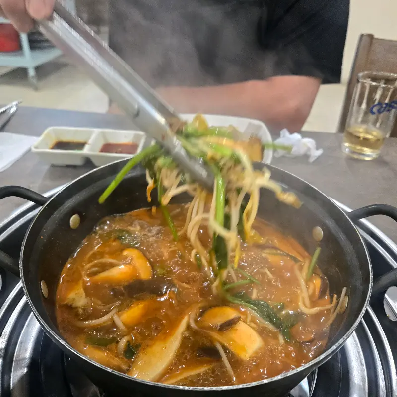 미나리를 듬뿍 집어올려 샤브샤브 냄비에 넣는 모습