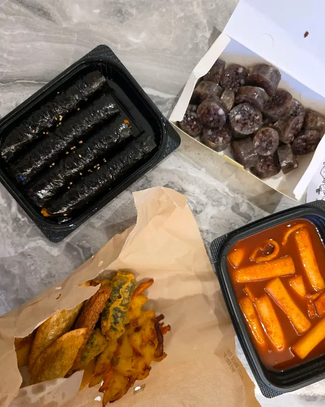 꼬마김밥, 순대, 떡볶이, 튀김이 담긴 포장 음식 사진