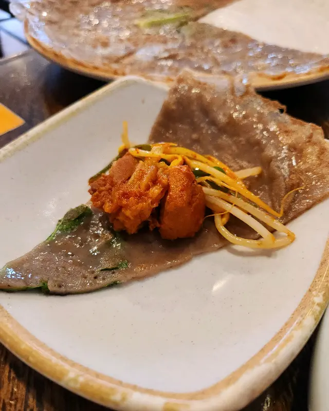 메밀전에 갈비찜을 싸서 먹는 모습