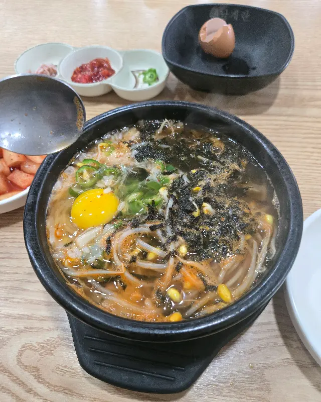 숟가락으로 콩나물 국밥을 떠먹는 모습