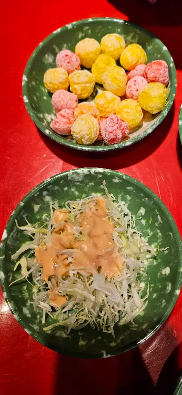 접시에 담긴 샐러드는 신선해 보였다. 양배추는 아삭아삭해 보였고, 소스는 달콤해 보였다. 샐러드 옆에는 알록달록한 과자가 담겨 있었다.