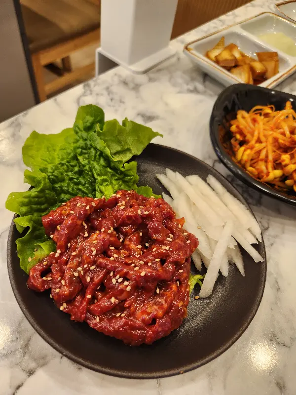 육회 한 접시가 검은색 접시에 담겨져 있다.