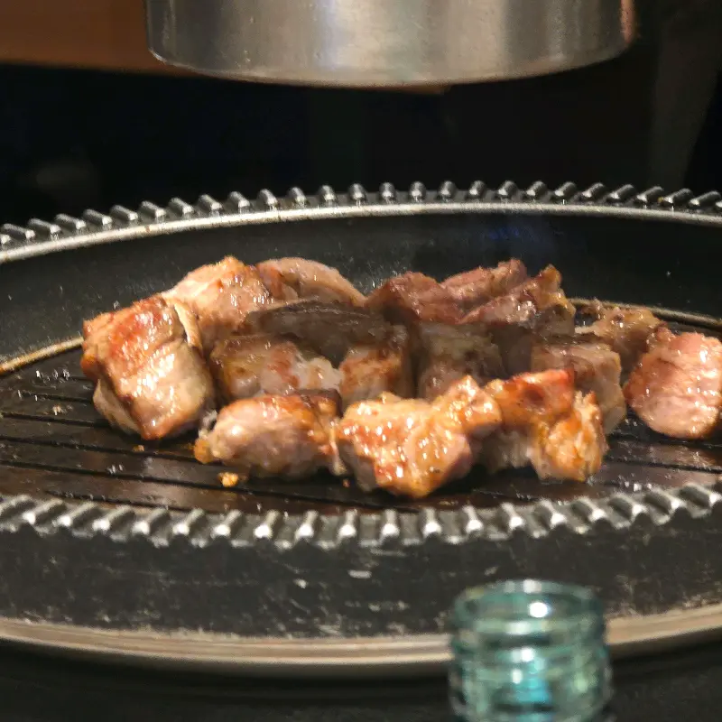 불판 위에서 먹기 좋게 잘린 돼지고기가 맛있게 구워지고 있는 모습