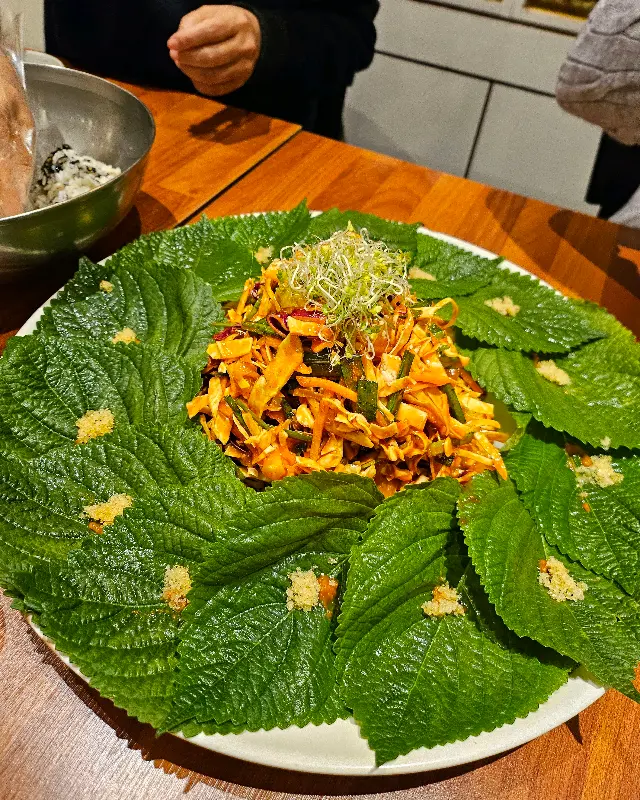 깻잎 위에 회무침을 듬뿍 올려 싸 먹는 모습