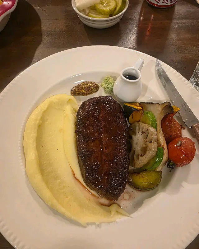 스테이크와 가니쉬가 조화롭게 담긴 접시