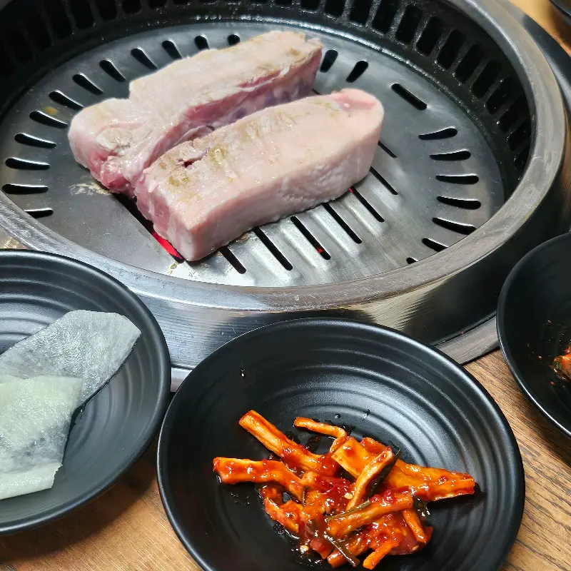 두툼한 삼겹살이 불판 위에서 맛있게 익어가는 모습