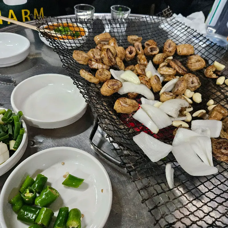 숯불 위에서 익어가는 막창과 마늘, 양파