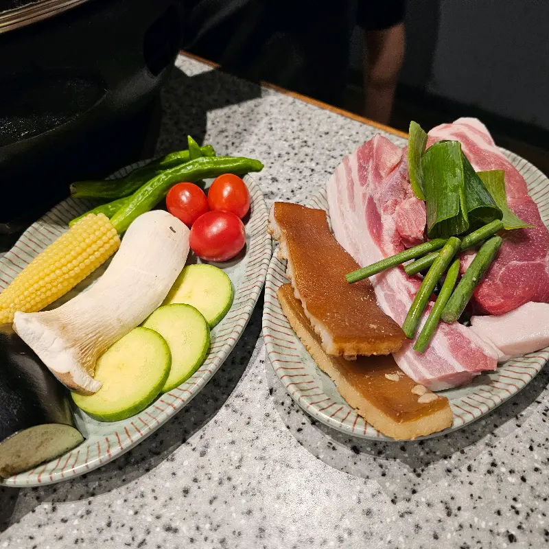 불판 위에 돼지고기와 채소가 함께 구워지고 있는 모습