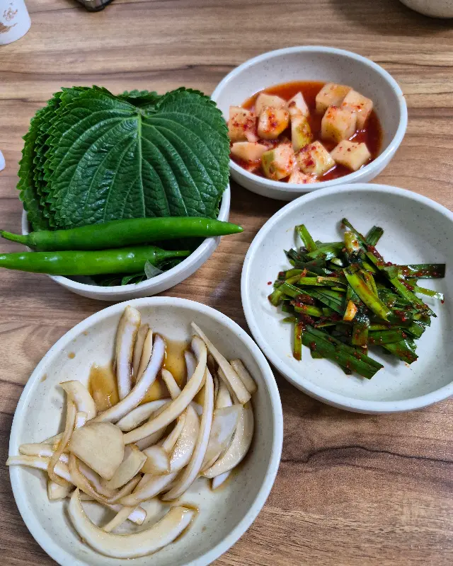 싱싱한 깻잎과 고추, 밑반찬이 담겨 있는 모습