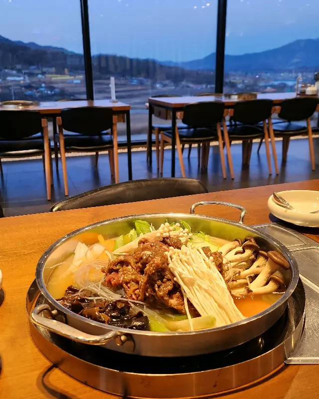 소불고기 전골이 끓고 있는 모습과 창밖으로 보이는 설경