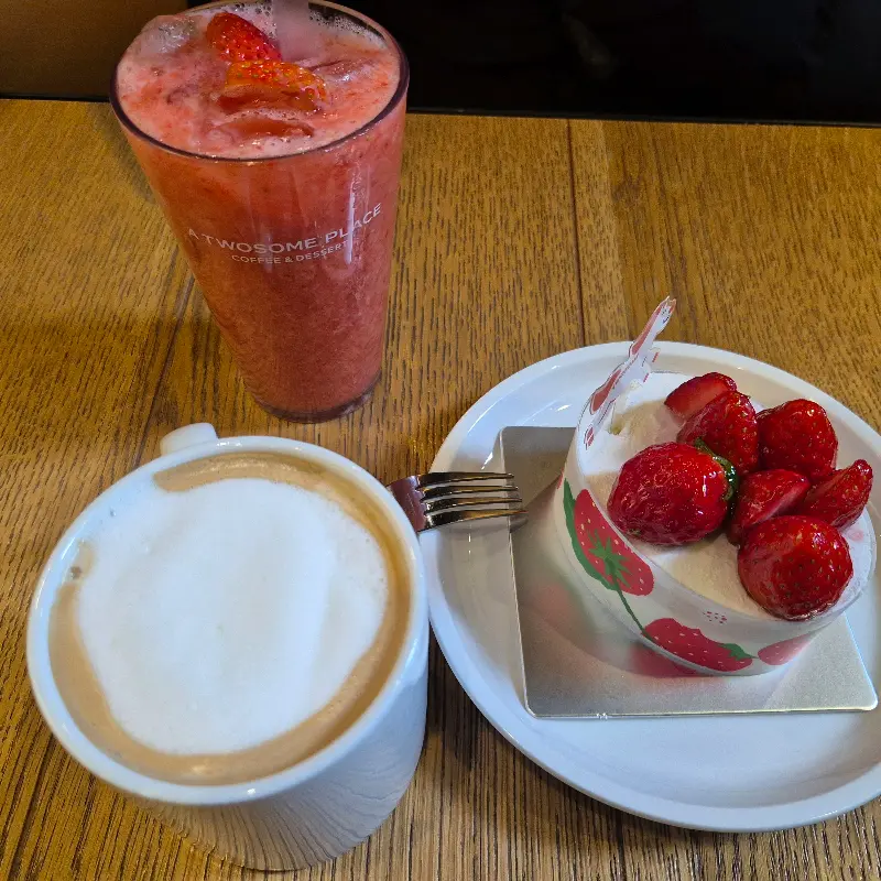 테이블 위에 놓인 스초생 케이크, 딸기 밀크 쉐이크, 그리고 따뜻한 라떼