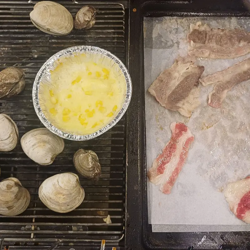 조개와 고기가 함께 구워지는 모습