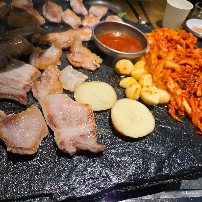 돌판 위에 구워지는 삼겹살과 김치